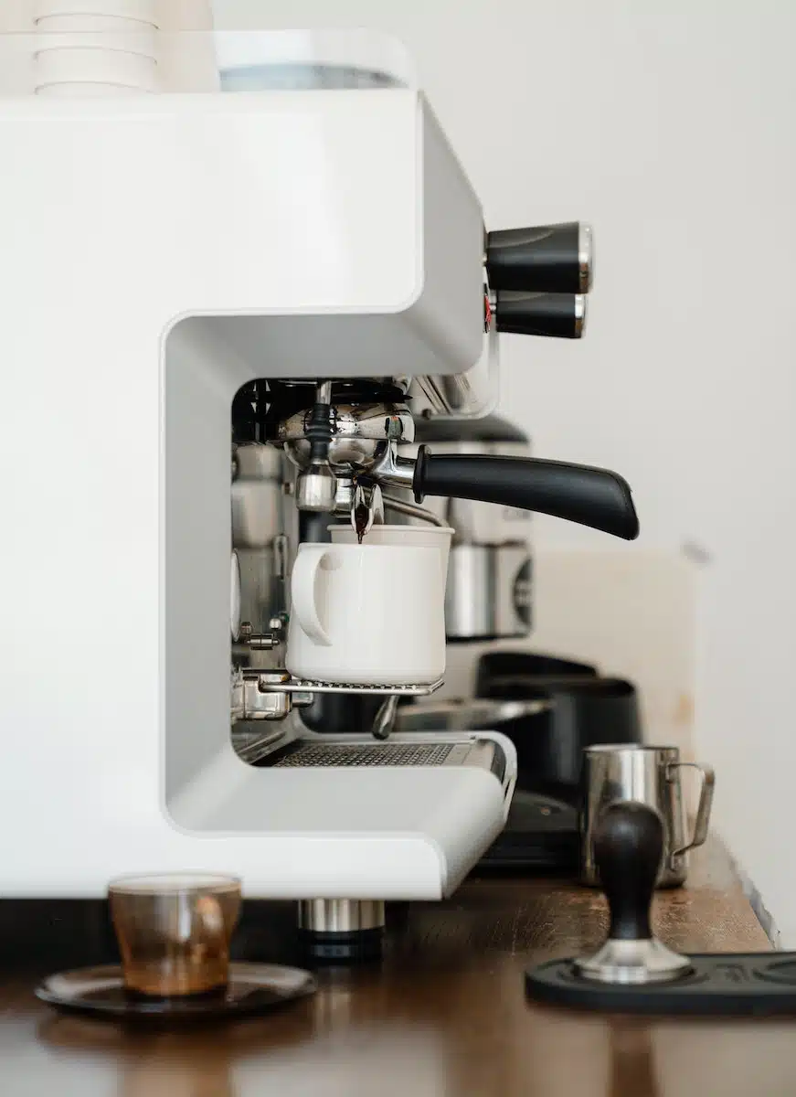 Coffee machine pouring cappuccino into cup in modern cafe