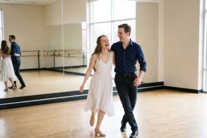 Couple de mariés répétant leur ouverture de bal dans un studio de danse avec miroirs et parquet en bois