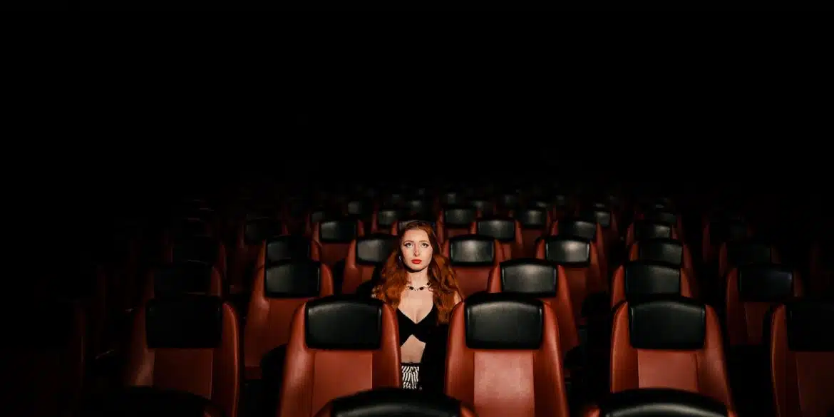 a woman in a black dress sitting in a theater